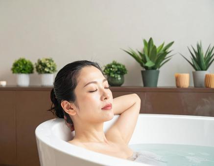 バスタイムに浴槽でリラックスする女性 バスタイムに浴槽でリラックスする女性の写真