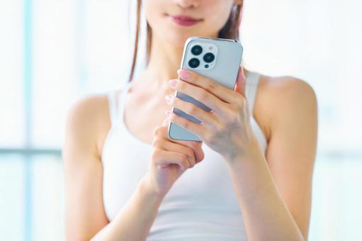 スマホを見るトレーニング中の女性の手元 スマホ,女性,トレーニングの写真素材
