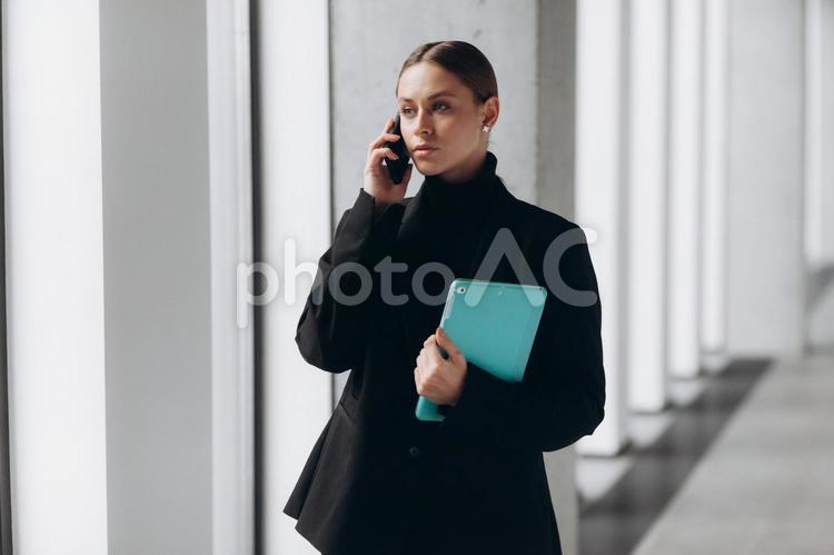 タブレットを持ちながら通話している女性 女性,電話,スマートフォンの写真素材