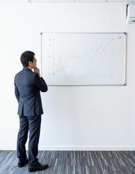 チャートを見て検討する男性ビジネスマンの写真