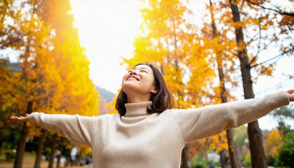 紅葉の中で深呼吸する秋服の日本人女性 紅葉の中で深呼吸する秋服の日本人女性の写真