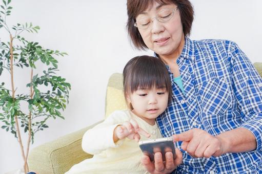 おばあちゃんとスマホを使う子供 おばあちゃんとスマホを使う子供 子育て,幼児,セルフィーの写真素材