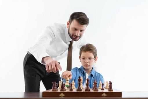 男の子にチェスを教えるお父さん(白背景) 男の子にチェスを教えるお父さん(白背景)の写真