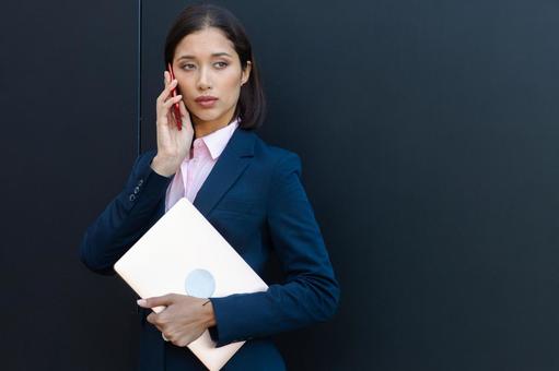 オフィスビルの黒い壁の前で電話するビジネスウーマン ビジネスウーマン,ビジネス,女性の写真素材