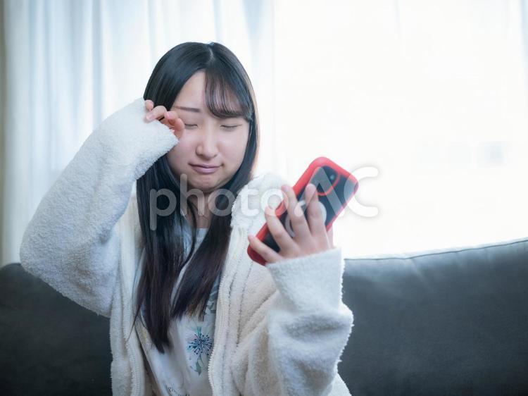 16：寝起きの女の子 スマホ,スマホチェック,携帯電話の写真素材
