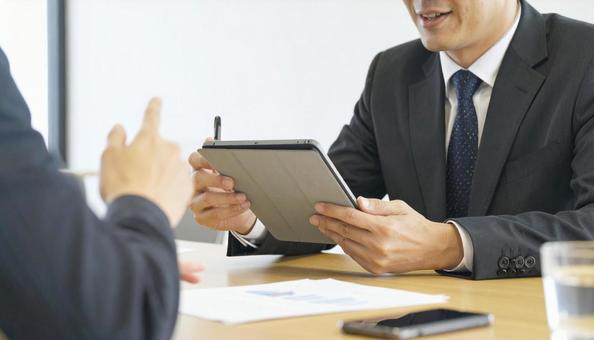 タブレットを使って説明する男性営業マン タブレットを使って説明する男性営業マンの写真