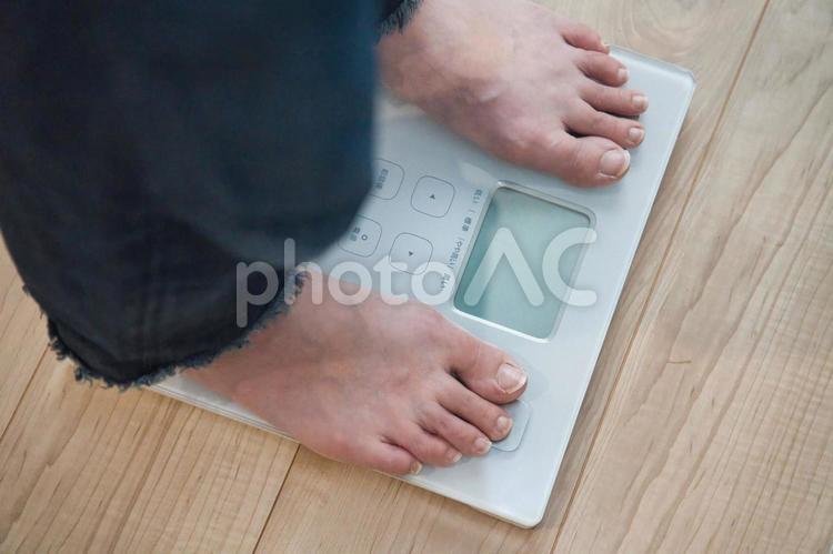 リビングで体重計にそっと足を乗せる女性 体重計,体重管理,健康維持の写真素材