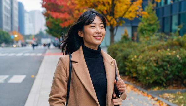 秋のオフィス街を歩く笑顔の女性 秋のオフィス街を歩く笑顔の女性の写真