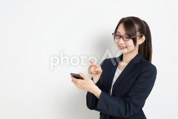 スマートフォンで検索をしているメガネのビジネスウーマン（コピースペース） 女,女性,日本人の写真素材