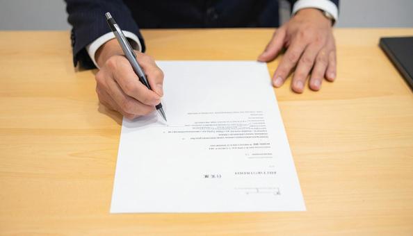 契約書にサインをするビジネスマン 契約書にサインをするビジネスマンの写真