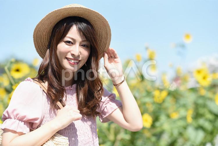 ひまわり畑と麦わら帽子を被る笑顔の女性 女性,ひまわり,夏の写真素材
