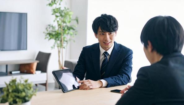 タブレットを使って説明する男性営業マン タブレットを使って説明する男性営業マンの写真