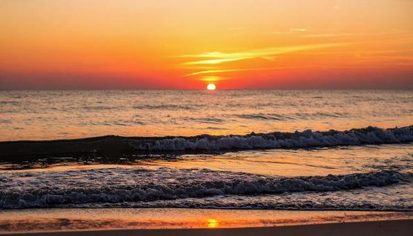 太陽が沈む夕暮れの海辺、サンセットビーチの写真