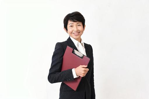 笑顔でファイルを持つスーツ姿のミドル女性 笑顔でファイルを持つスーツ姿のミドル女性 ビジネス,女性,会社員の写真素材