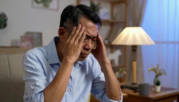 頭を抱えて落ち込む日本人男性 頭を抱えて落ち込む日本人男性の写真