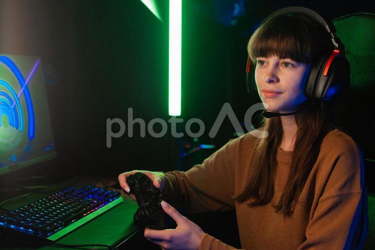 コントローラーを持ってヘッドセットを付けてゲームする女性 ゲーマー,人物,女性の写真素材