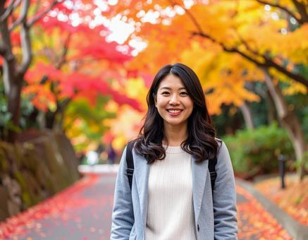 紅葉の道を散歩する女性の写真