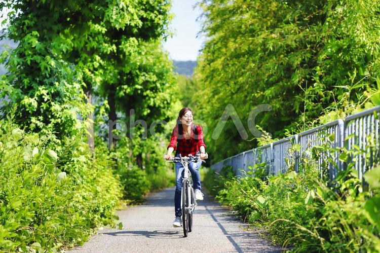 緑の中を自転車で走行する女性 さわやか,女性,ポートレートの写真素材