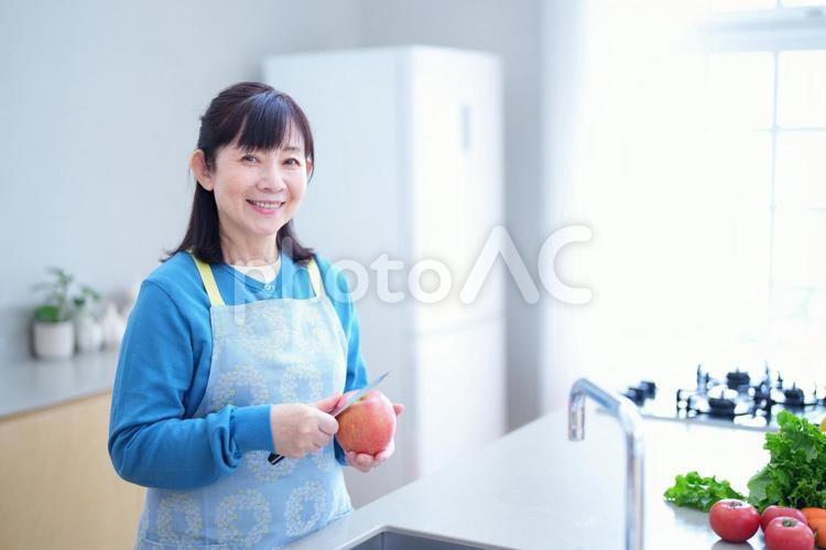 キッチンでりんごを調理する笑顔の女性 主婦,家政婦,エプロンの写真素材