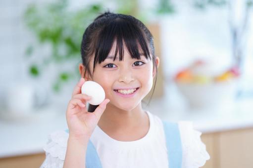 キッチンで卵を手に持つ子どもの笑顔 女の子,小学生,日本人の写真素材