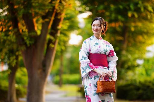 浴衣姿の女性が木陰の道を歩く 女性,微笑む,歩道の写真素材