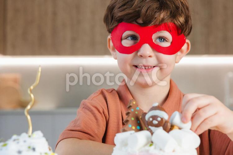 ケーキを飾り付ける仮面をつけた男の子 ケーキ,スイーツ,デザートの写真素材