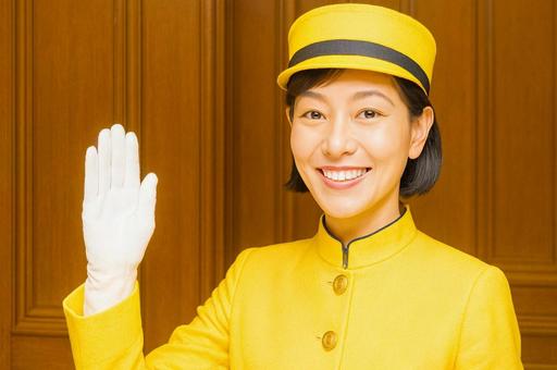 笑顔で手を挙げるホテルスタッフの女性の写真