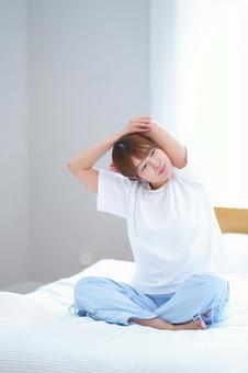 胡坐で腕のストレッチをする女性 女性,ストレッチ,ベッドの写真素材