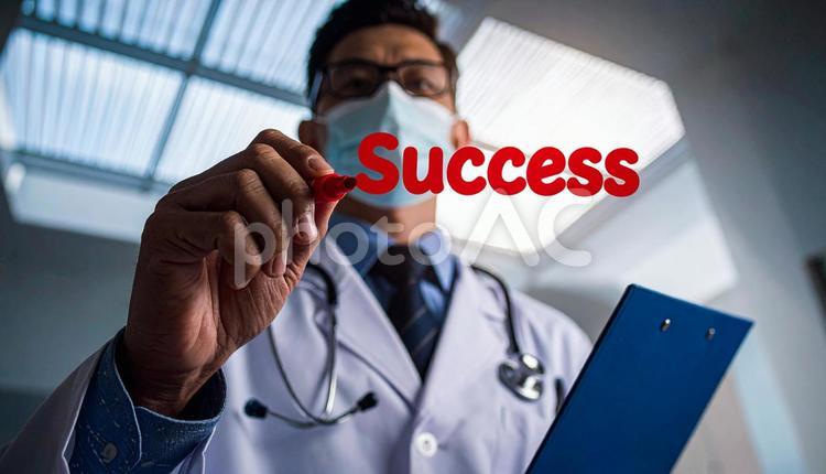 「SUCCESS」を書く男性医師の手もと 成功,入院,英単語の写真素材