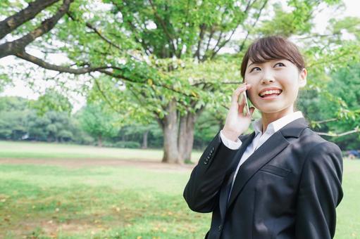 電話をするスーツ姿の若い女性 電話をするスーツ姿の若い女性 ほほえむ,ビジネスウーマン,笑うの写真素材