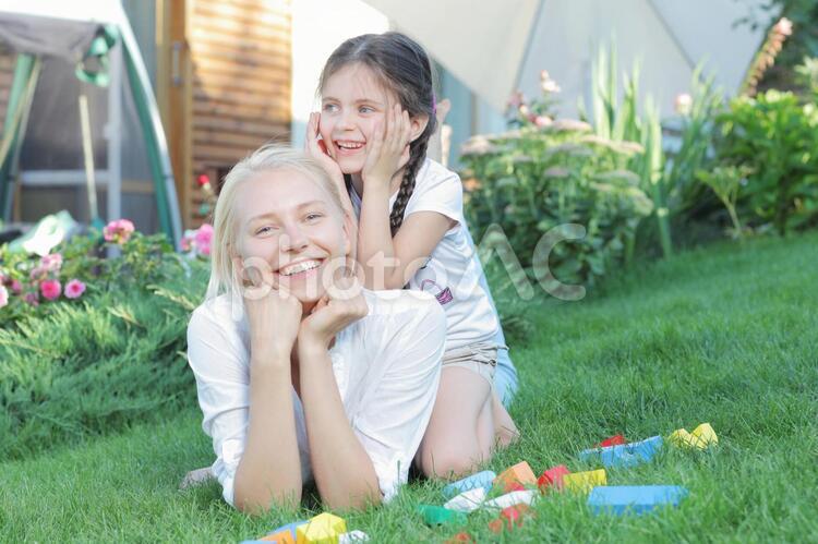 芝生の上に寝そべる母親の上に乗る女の子7 親子,外国人,屋外の写真素材