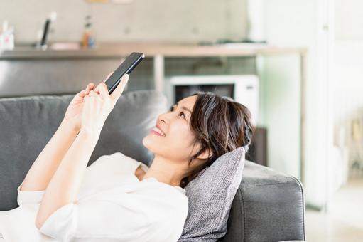 部屋でスマホを使う若い女性 部屋でスマホを使う若い女性 動画,電話,視聴者の写真素材