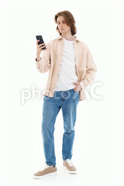 片手をポケットに入れながらスマホを持つ男性 男性,スマートフォン,持つの写真素材