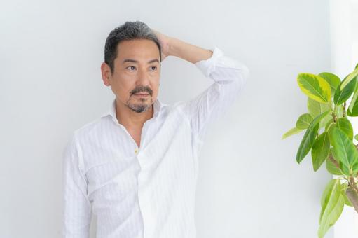 リビングでヘアケアをするミドルの男性 ヘアケア,育毛,ビューティーの写真素材