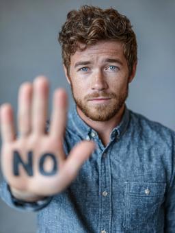 「NO」を掲げた真剣な表情の男性 「NO」を掲げた真剣な表情の男性の写真