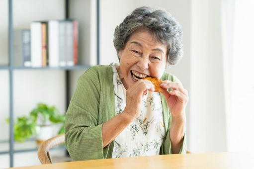 せんべいを食べるシニアの女性 せんべいを食べるシニアの女性 せんべい,煎餅,固いの写真素材