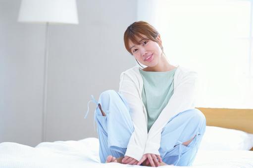 カメラ目線でベッドに座る笑顔女性 女性,笑顔,笑うの写真素材