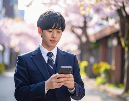 スマホを操作する男子高校の写真