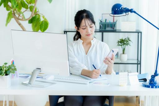 オフィスでスマホを持つビジネスウーマン スマホ,ビジネスウーマン,オフィスの写真素材