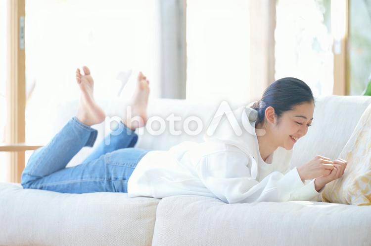 ソファーに寝転んで足をあげて爪を見ている女性 女性,人物,30代の写真素材