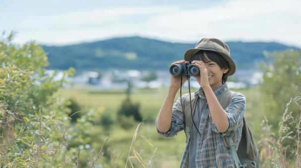 晴れた丘でのバードウォッチングする少年 晴れた丘でのバードウォッチングする少年の写真