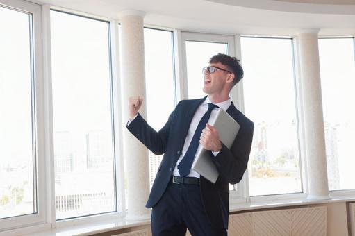 パソコンを持ち叫ぶ男性 男性,外国人,ガッツポーズの写真素材