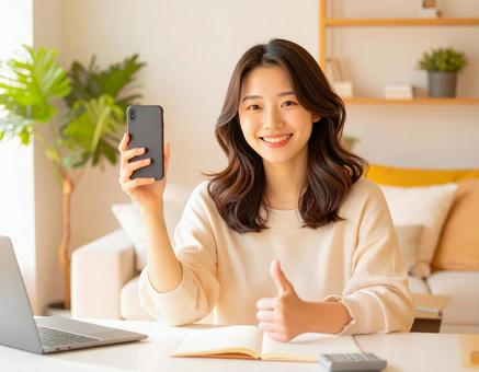 家計がうまくいきスマホ片手に微笑む女性 家計がうまくいきスマホ片手に微笑む女性の写真