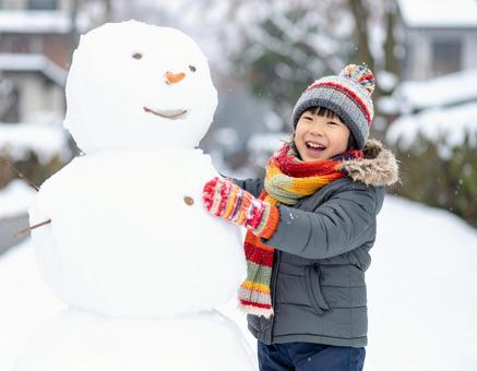 雪だるまを作って喜ぶ子供の冬の屋外風景の写真