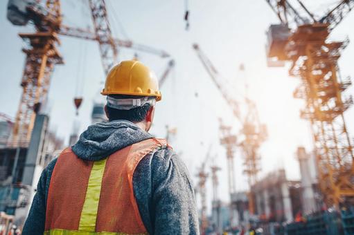 建設中のビルと、その進捗を見守る作業員の写真