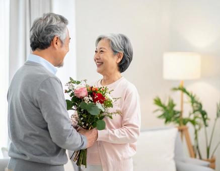記念日に花束を贈る夫のシニア夫婦の写真