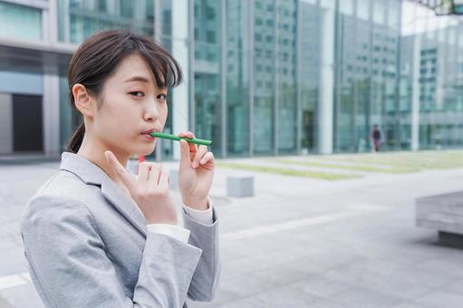 電子タバコを吸う若いビジネスウーマン 電子タバコを吸う若いビジネスウーマンの写真