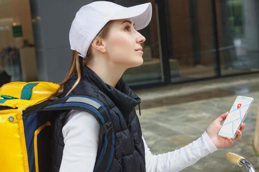 スマートフォンの地図を使うフードデリバリーの女性 配達,フードデリバリー,デリバリーの写真素材