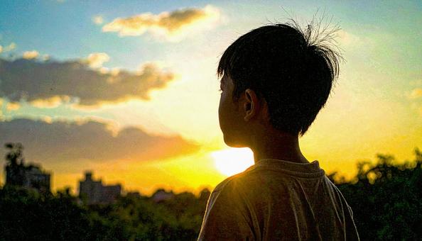 夕焼けの空を見つめる日本人の少年 夕焼けの空を見つめる日本人の少年の写真