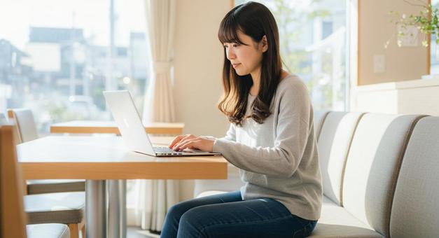 カフェでノートパソコンをする女性 カフェでノートパソコンをする女性の写真